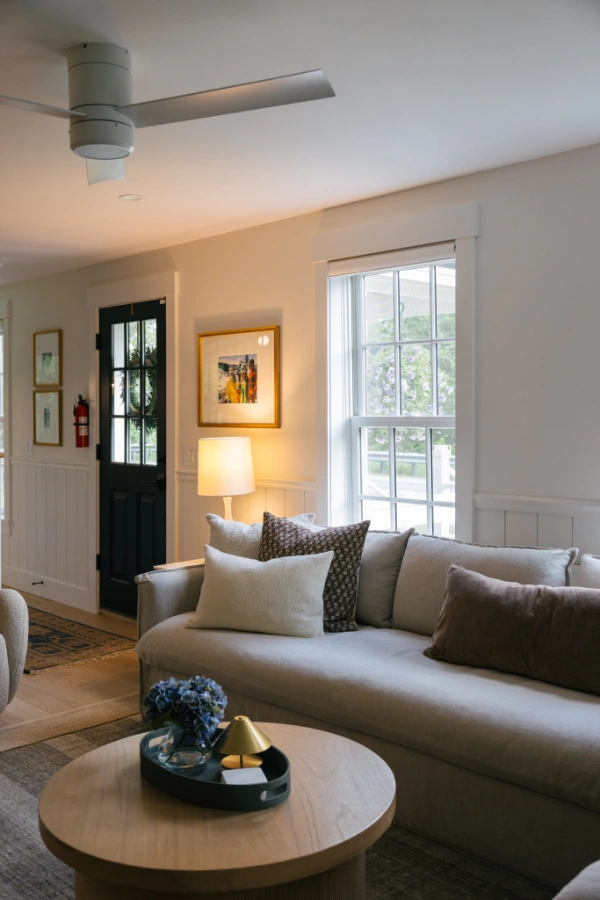 Comfortable living area with plush sectional sofa, throw pillows, warm wood accents, and natural daylight from tall windows